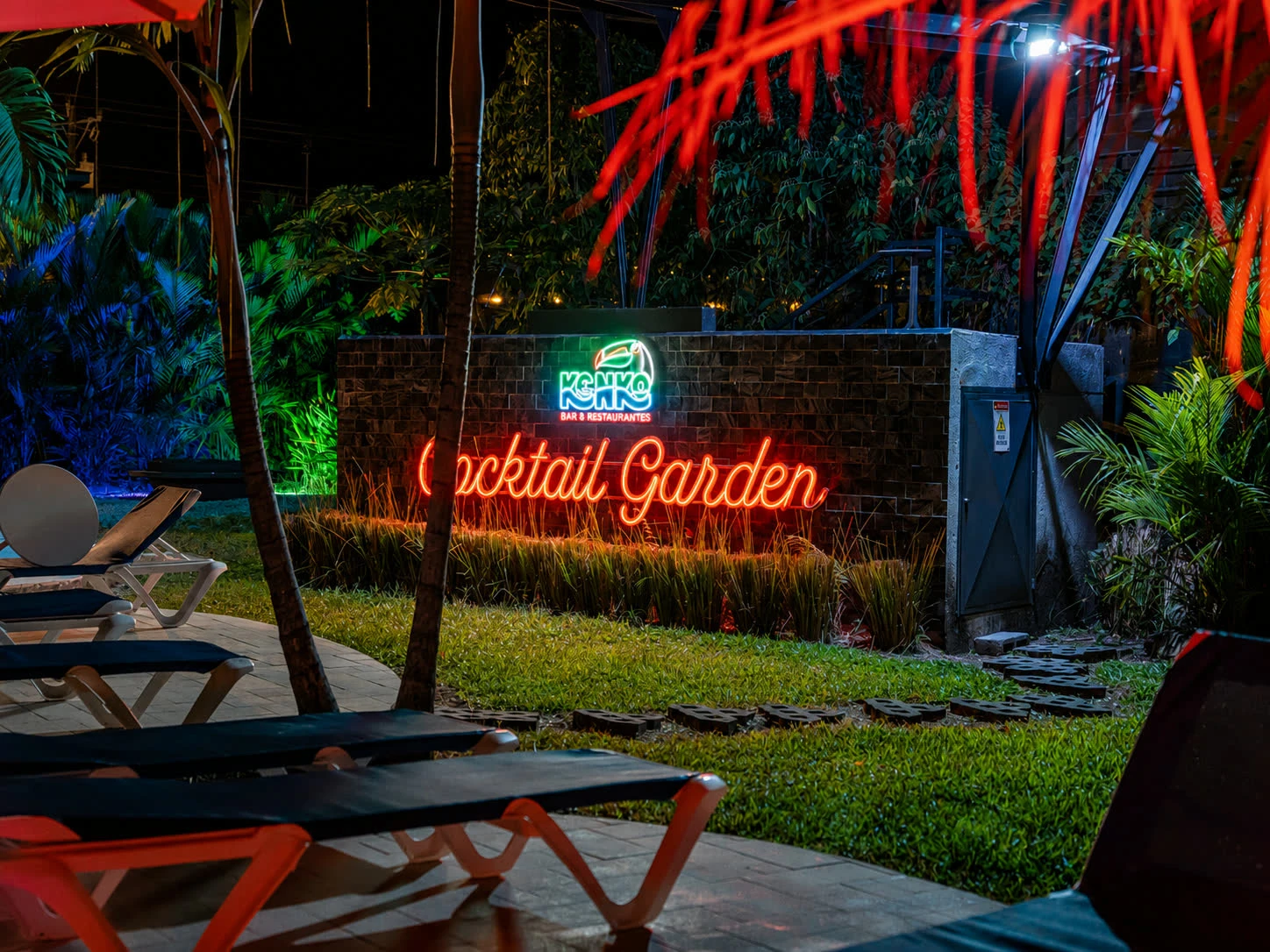 The Kenko Cocktail Garden neon sign beside the pool at night